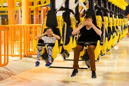 Smiling family riding on a rollercoaster at an amusement park.