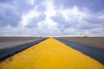 Closeup yellow runway marking on concrete in airport and beautiful blue sky (selective focus)