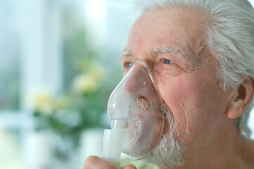 Close up portrait of ill senior man portrait with inhaler