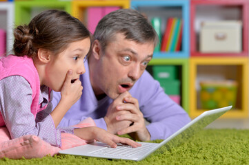 Portrait of father with little daughter using laptop