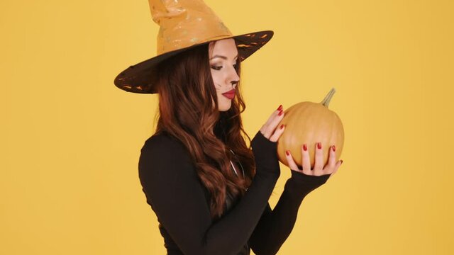 Woman in halloween makeup holding pumpking on orange background