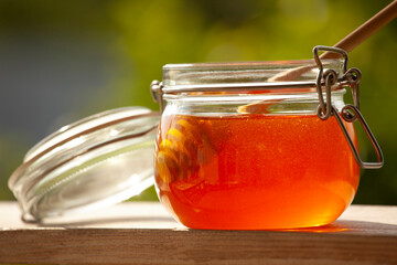 Honey in glass jar on a wooden table nature background