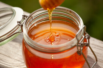 Honey in glass jar on a wooden table nature background