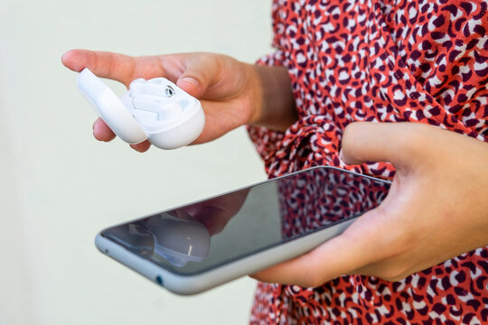 Anonymous female on mobile phone and wireless earphones