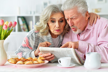 Close up portrait of happy senior couple reading newspaper