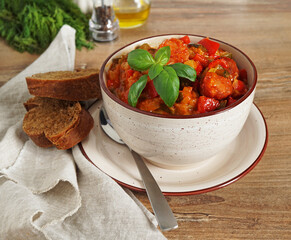  traditional Spanish dish pisto with sausages in a deep bowl on a wooden background