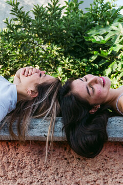 Dreamy girlfriends resting on bench in park