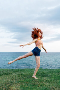 Woman gracefully dancing on grassy seashore
