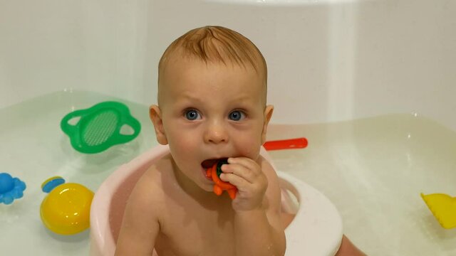 Small child in the bathroom. Smiling kid in the bathroom with colorful toys.