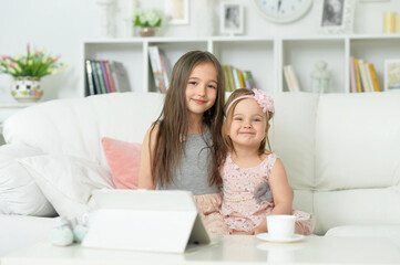 Obraz na płótnie Canvas two cute little girls sitting on sofa