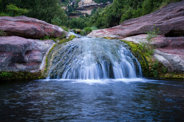Fototapeta na wymiar waterfall between red rocks, natural pools and moss, sant miquel del fai catalonia, spain