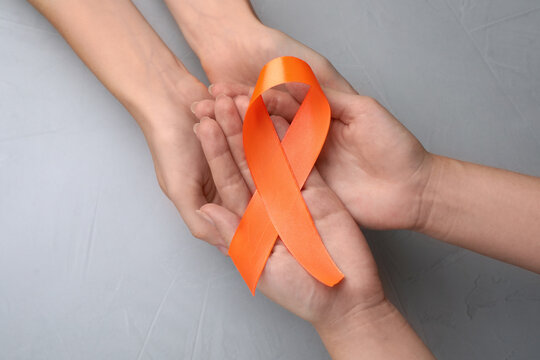 Couple holding orange ribbon on light grey background, top view. Multiple sclerosis awareness - Powered by Adobe