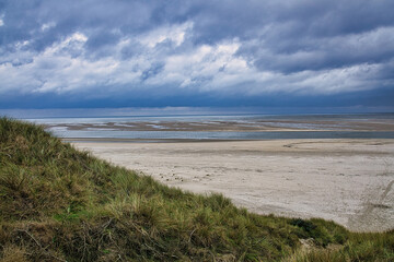 Fototapeta na wymiar dramatic clouds on the beach in denmark between the dunes