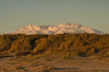 piled up clouds behind the dunes on the beach
