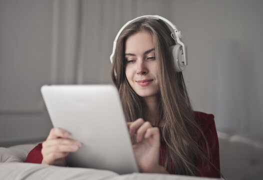 young woman uses a tablet and listens to music