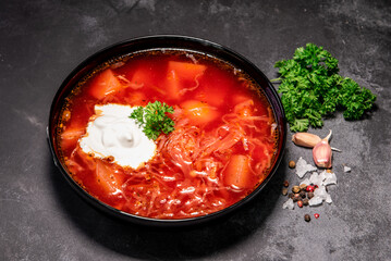 Borsch. Ukrainian soup. Red soup. Borsch with sour cream and onions, white bread. Traditional Russian borsch with sour cream. The concept of delicious food with sour cream on a black background