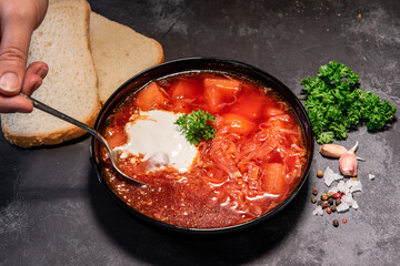 Borsch. Ukrainian soup. Red soup. Borsch with sour cream and onions, white bread. Traditional Russian borsch with sour cream. The concept of delicious food with sour cream on a black background
