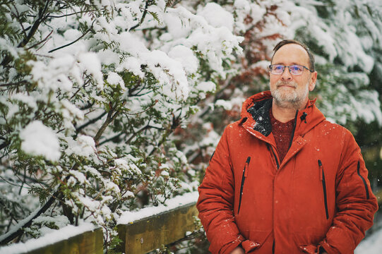 Outdoor portrait of middle age man, 55 - 60 years old, enjoying nice cold day, wearing red orange winter jacket