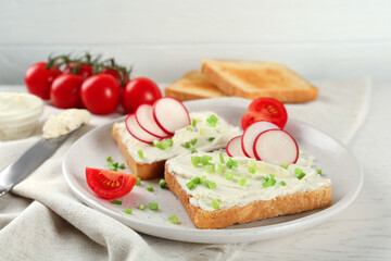 Fototapeta na wymiar Toasted bread with cream cheese and vegetables on white wooden table