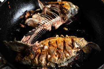 Eaten fried crucian carp in a pan. Fried fish spine and bones.