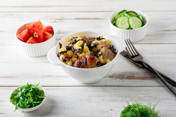 Pasta with meat and basil, chopped vegetables, tomatoes, cucumbers on a wooden white plate.