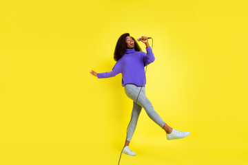 Fototapeta na wymiar Full size portrait of excited attractive dark skin girl arm hold mic dancing isolated on yellow color background