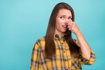 Photo of irritated young girl arm fingers hold cover nose look empty space isolated on blue color background