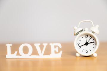 Time fot love: Love caption and white wintage clock on the wooden table