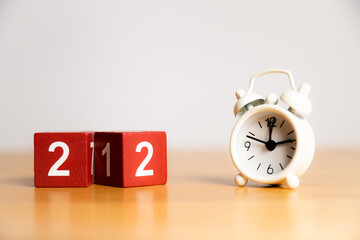 New Year 2022 - changing 21 cube. White little clock on a wooden table