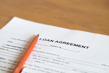 Empty loan agreement form and orange pen on the wooden table