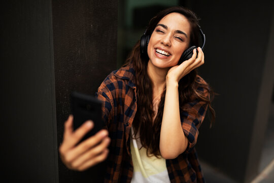 Young Smiling Woman With Headphones Outdoors. Beautiful Happy Girl Listening The Music.