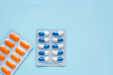 Different tablets, pills, capsule medicines blister packs, on blue background. Health care concept. Vitamins.	