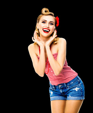 Portrait photo of excited surprised, very happy beautiful blond woman. Pin up girl with open mouth and raised hands showing toothy smile. Retro vintage concept. Dark black background.