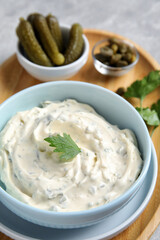 Tasty tartar sauce and ingredients on table, closeup