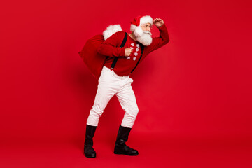 Full body profile side photo of santa look forward carry heavy bag present noel isolated over red...