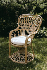 Close-up of rustic wicker chair with white cushion outdoors.