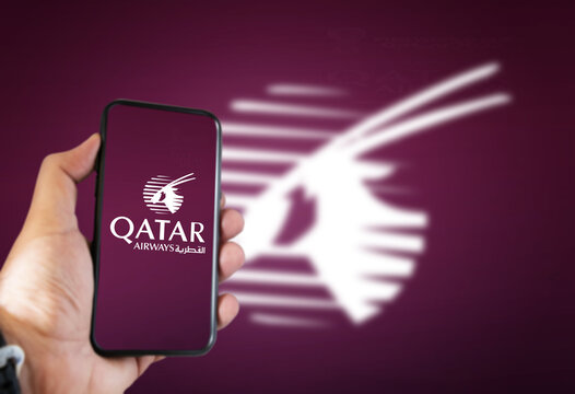 A hand holding a phone with the Qatar Airways airline app on the screen