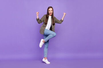 Full size photo of smiling positive young female raise fists in victory success triumph isolated on violet color background