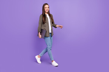 Full size profile side photo of smiling cheerful female go walk with laptop isolated on vivid violet color background