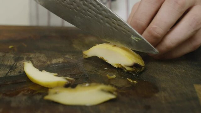 Slicing abalone seafood mollusk on cut board with kitchen knife. Close up.
