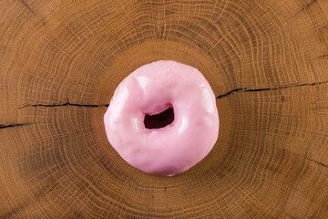 Glazed donut with strawberry, raspberry flavor on a wooden background