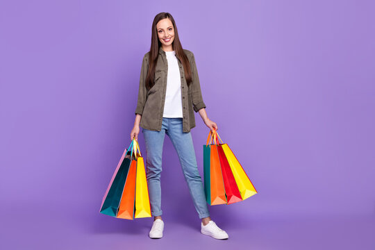 Full size photo of smiling cheerful female hold shopping bags purchase buy stuff isolated on violet color background