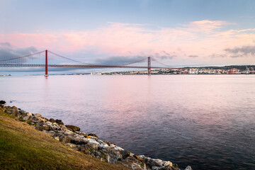 the 25 de Abril suspension bridge over Tagus river in Lisbon, Portugal at sunrise