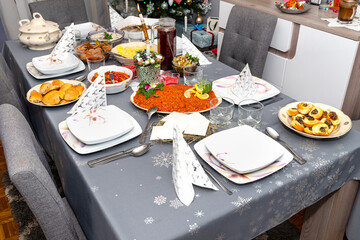 A table set before the supper for Christmas in Poland, visible baked fish fillets in a carrot salad, a holy wafer and dumplings.