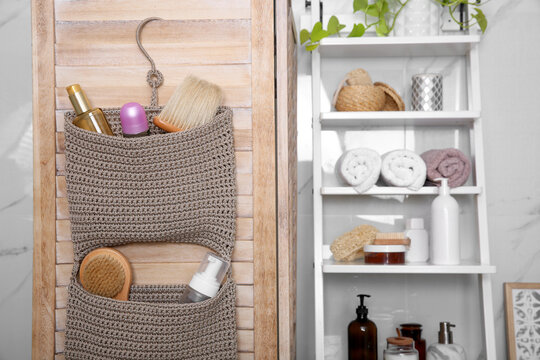 Knitted organizer hanging on wooden door in bathroom