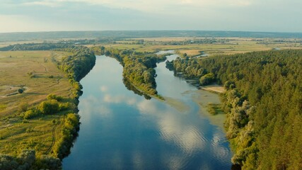 Naklejka na ściany i meble Aerial view above a beautiful landscape with a river while sunset. Aerial view from drone flies over a beautiful summer landscape. 