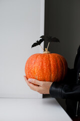 Woman in black jacket holding orange pumpkin with halloween decor