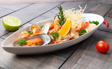 Assorted seafood in a plate. On a wooden background.