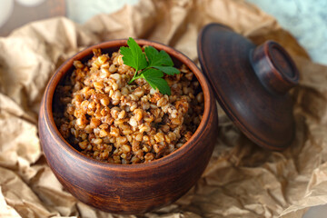 Bowl of buckwheat porridge with parsley on table, closeup