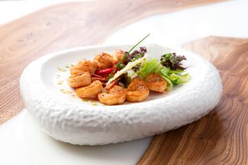 Fried shrimps in a plate on a wooden background.